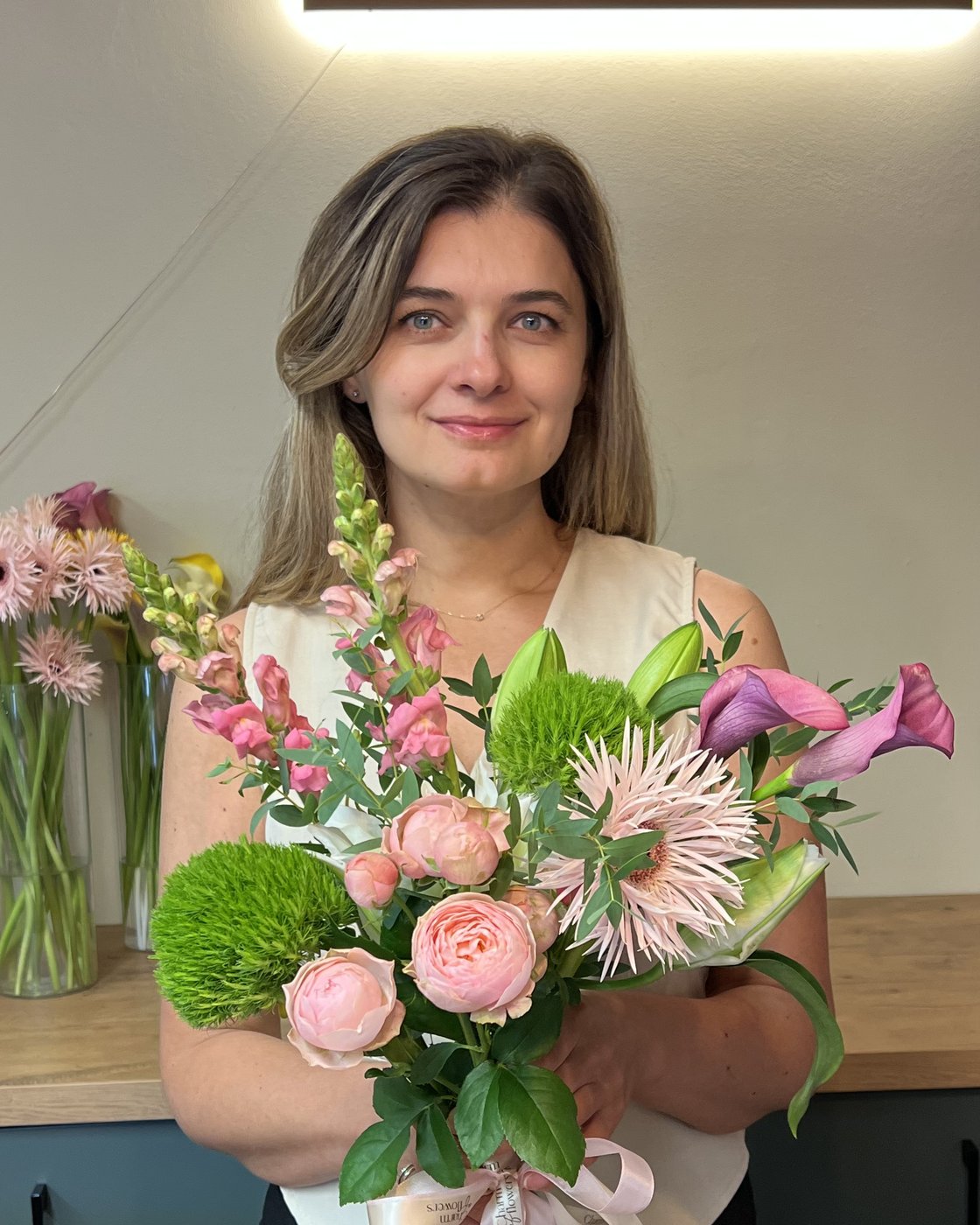 Floristka za pultem prodejny se dvěma kyticemi ze slunečnic